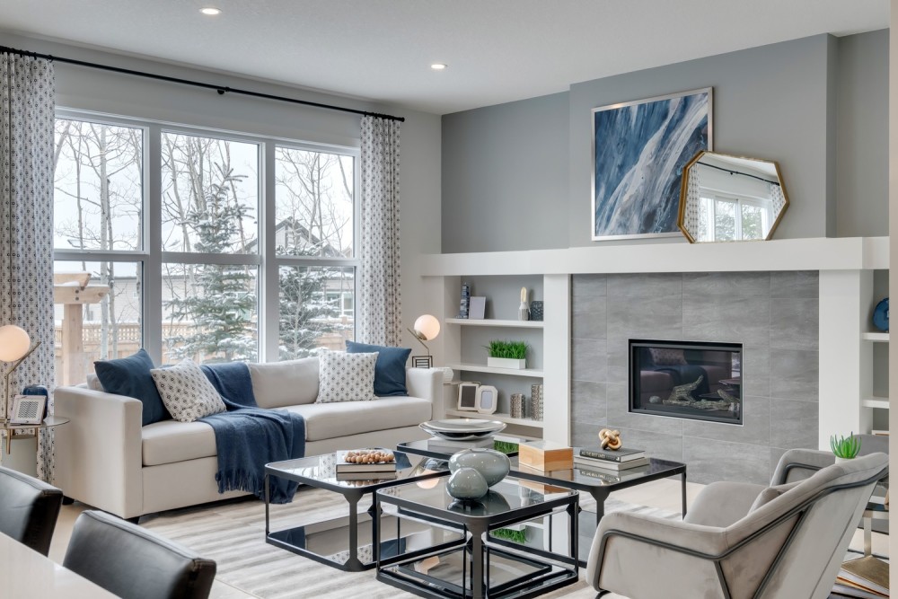 a modern living room in white and light grey tones with large windows and a fireplace