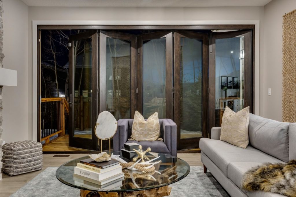 A modern living room with a foldable wall serving as a top to ceiling window and a patio door